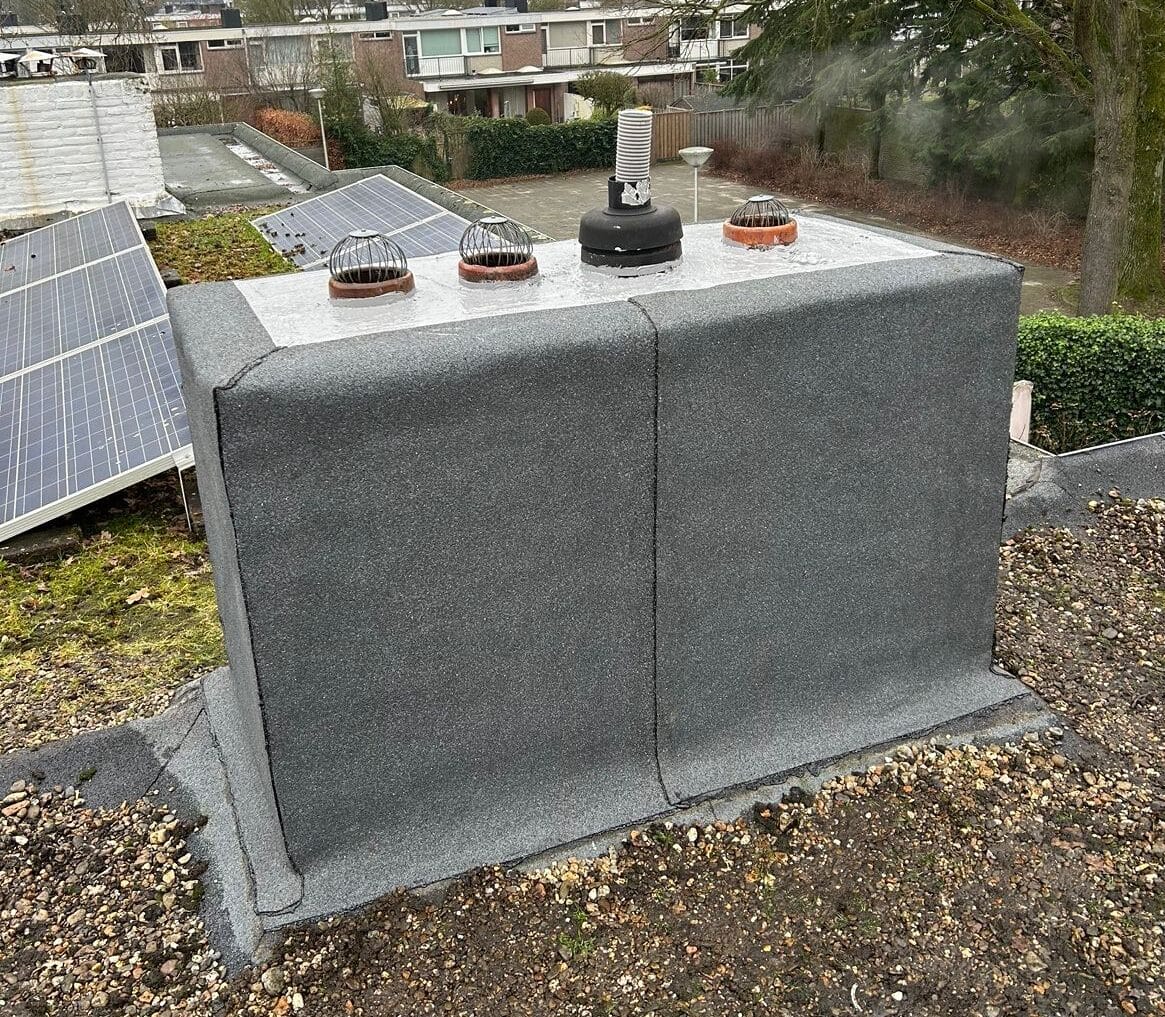 Op het dak staat een groot rechthoekig grijs blok met ventilatieopeningen, aangevuld met zonnepanelen als onderdeel van het dakverbouwingsproject.