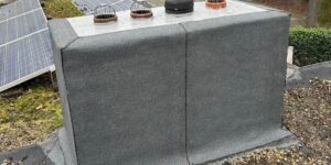 Op het dak staat een groot rechthoekig grijs blok met ventilatieopeningen, aangevuld met zonnepanelen als onderdeel van het dakverbouwingsproject.